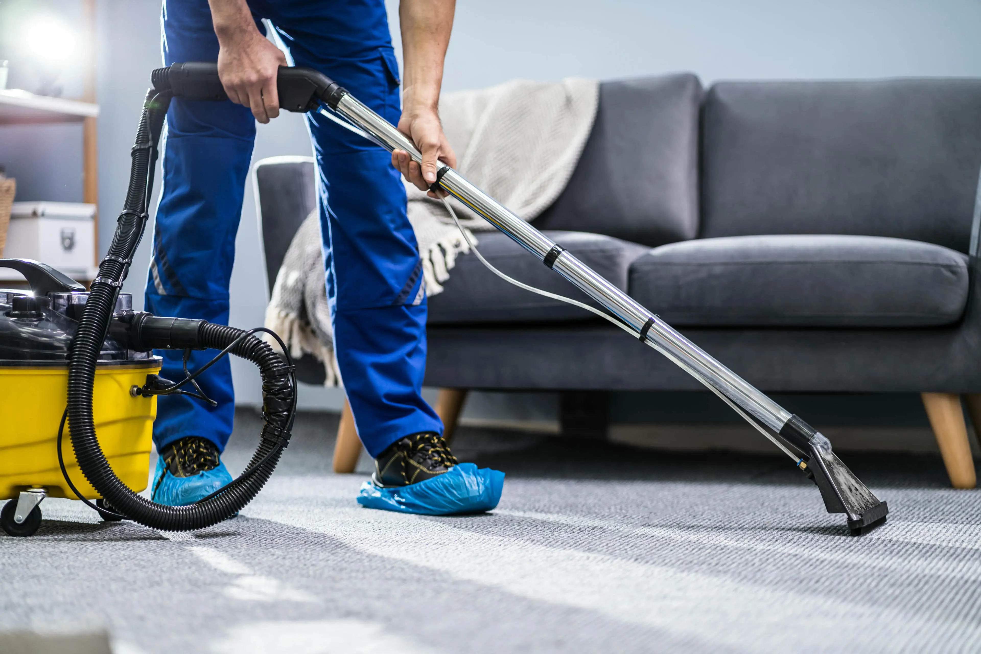 Person vacuuming carpet in living room.