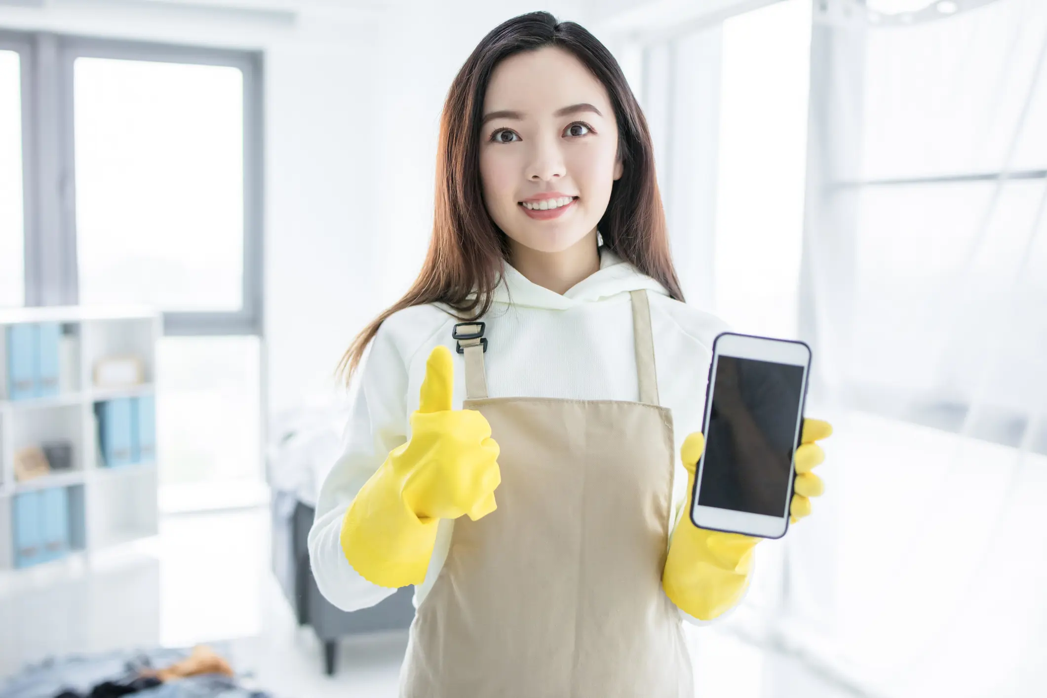 Woman in gloves holding phone, thumbs up.