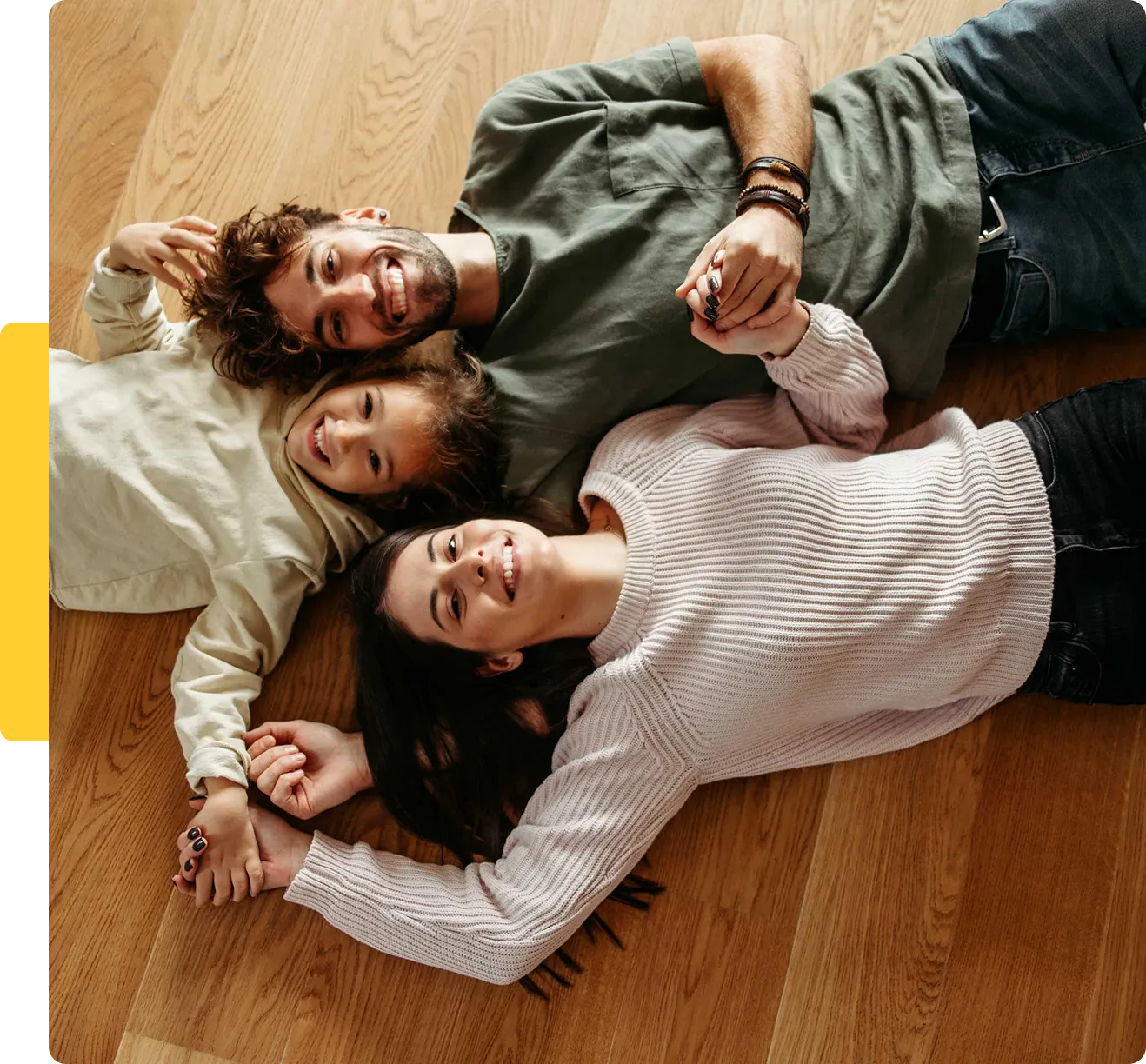 Happy family lying on wooden floor together.